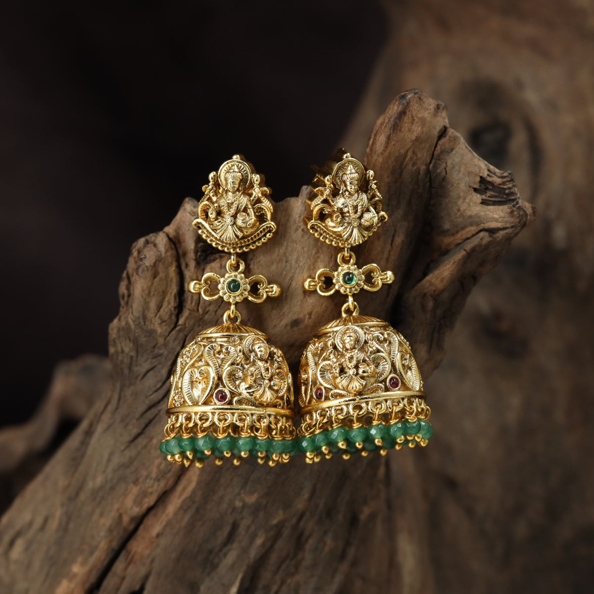 A grand antique Jumka pair showcasing sculpted Lakshmi, scrollwork and delicate bead drops