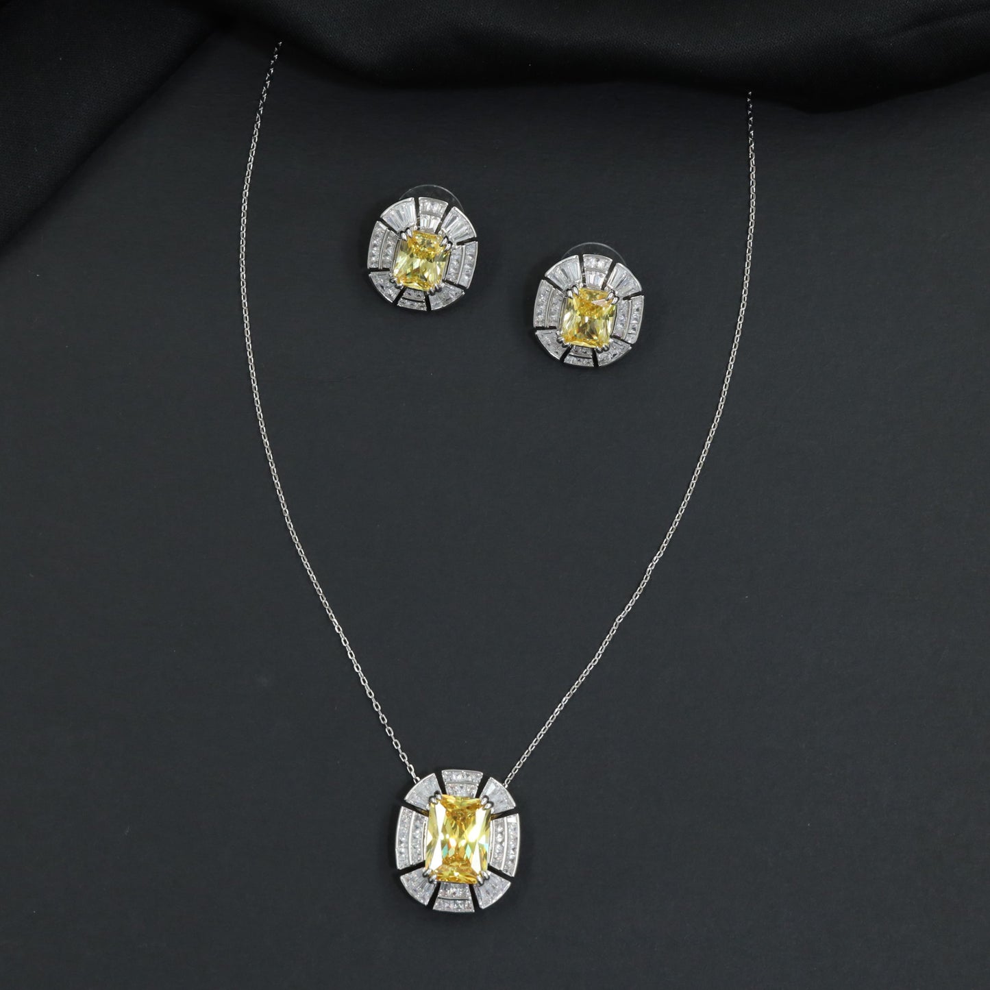 Contemporary pendant chain set with a structured medallion profile and matching stud earrings