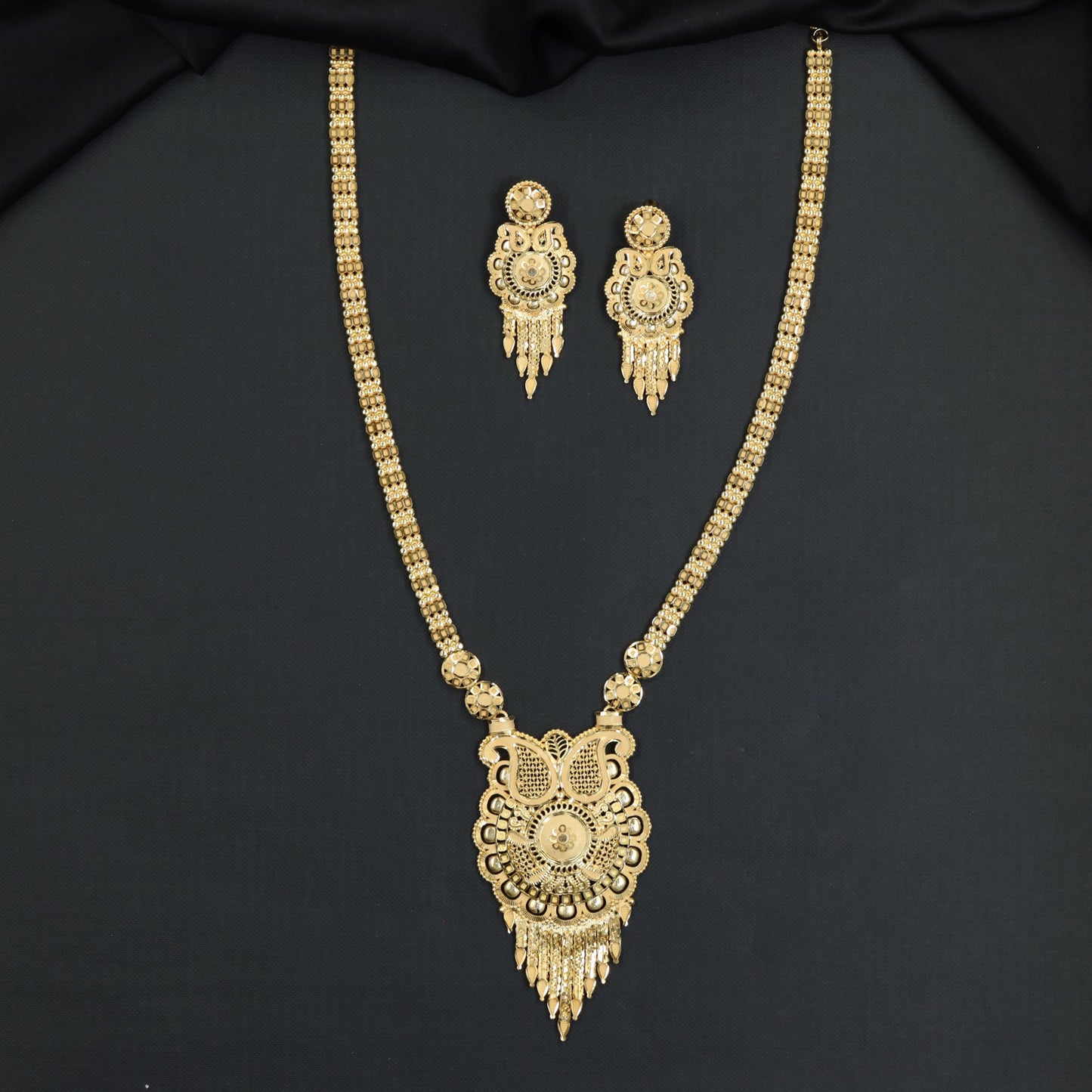 Forming Long Haara with ornate cutout locket and dangling tassel fringe