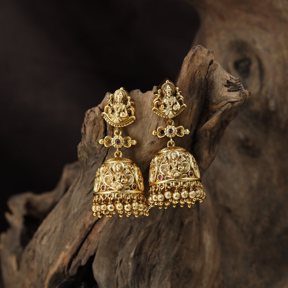 A grand antique Jumka pair showcasing sculpted Lakshmi, scrollwork and delicate bead drops