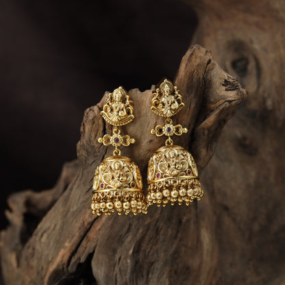 A grand antique Jumka pair showcasing sculpted Lakshmi, scrollwork and delicate bead drops
