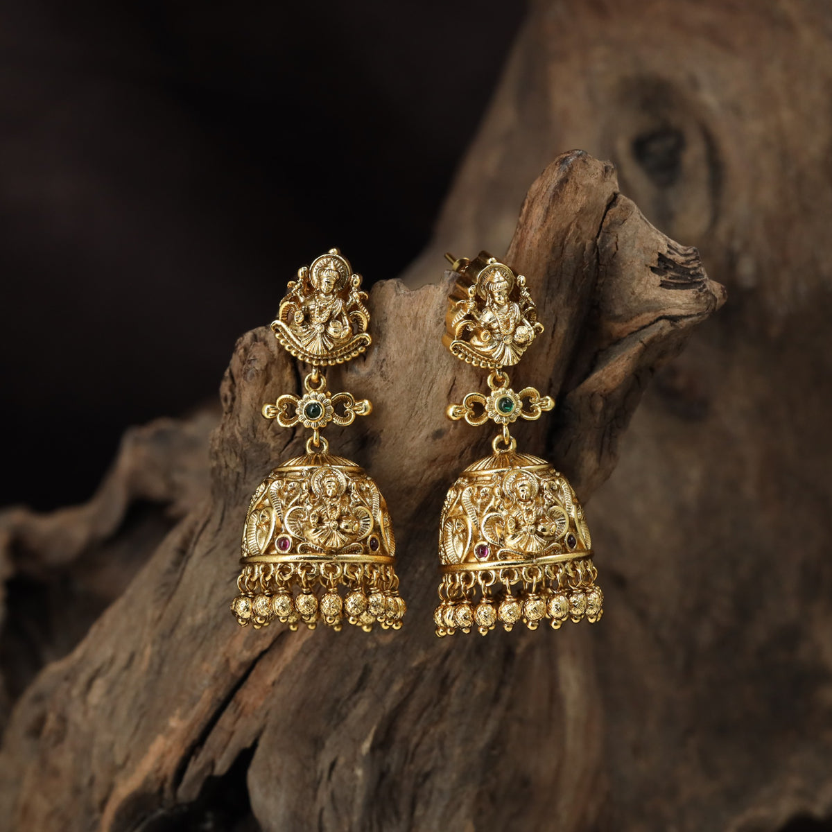 A grand antique Jumka pair showcasing sculpted Lakshmi, scrollwork and delicate bead drops