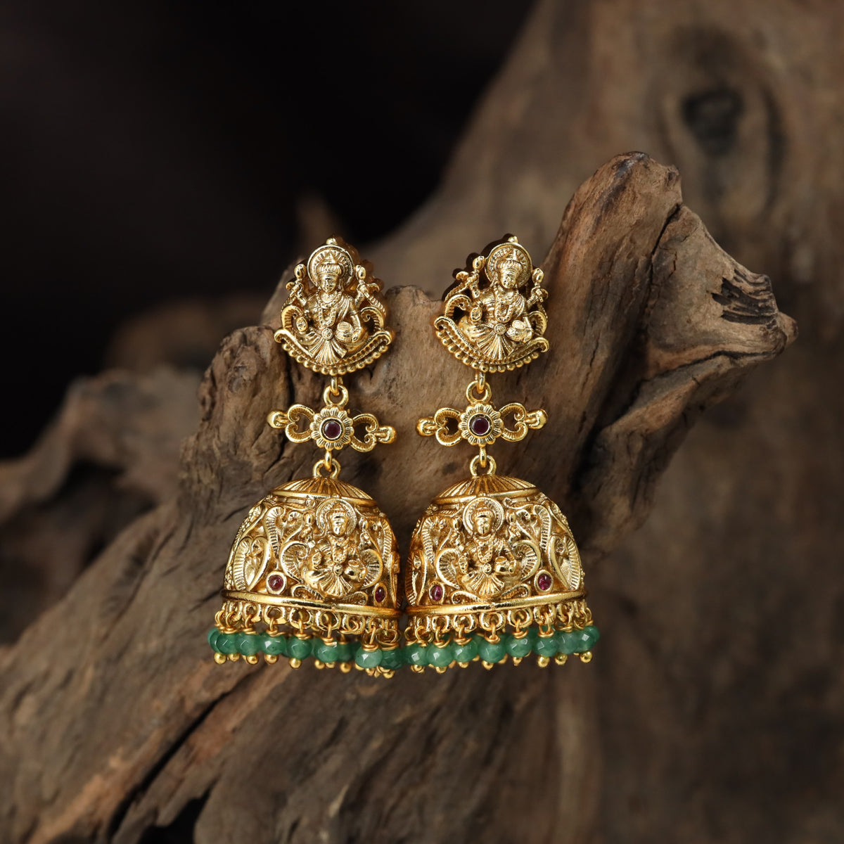 A grand antique Jumka pair showcasing sculpted Lakshmi, scrollwork and delicate bead drops