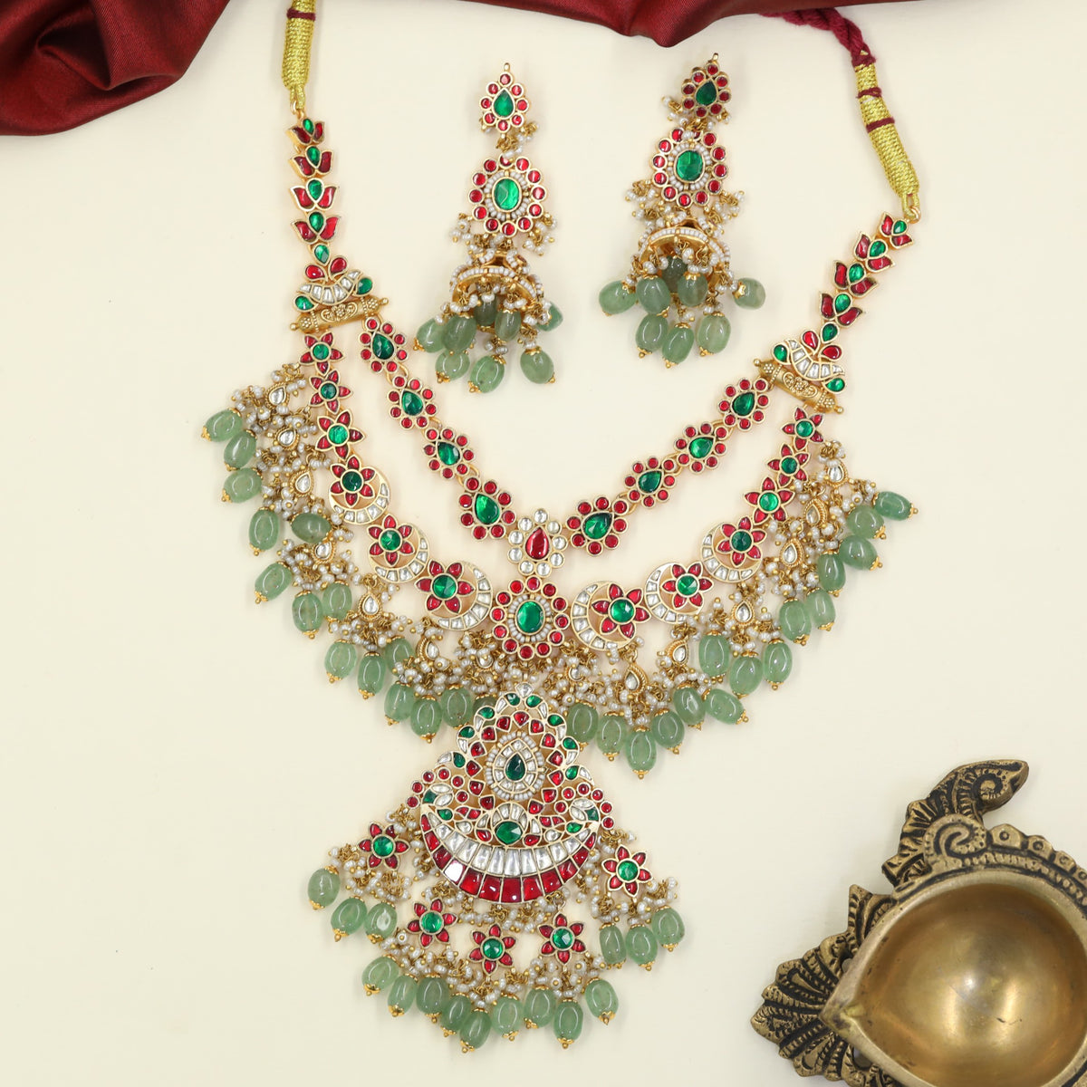 Jadau Necklace distinguished by sculpted flowers, curved borders and delicate dropwork