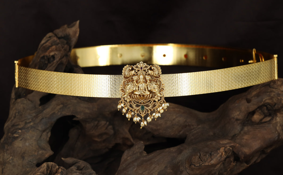 Seated Lakshmi with floral scrollwork and suspended drops