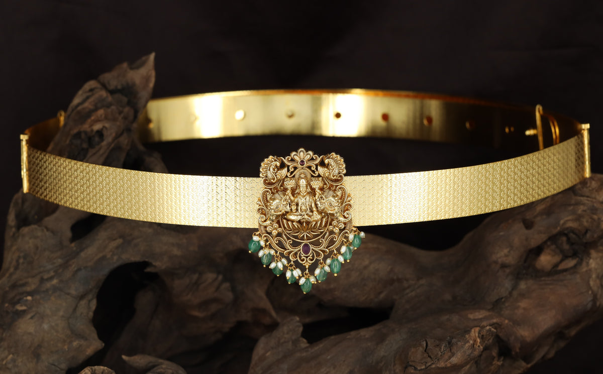 Seated Lakshmi with floral scrollwork and suspended drops