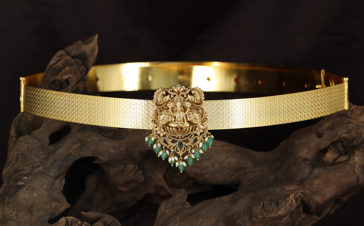 Seated Lakshmi with floral scrollwork and suspended drops